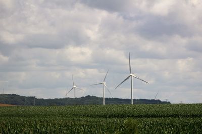 Wind turbines on field against sky