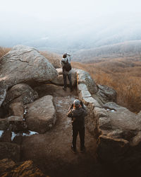 Rear view of man standing on rock against sky