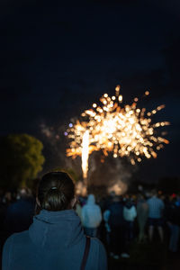 Rear view of woman against firework display at night