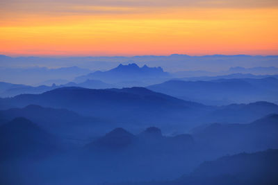 Scenic view of silhouette mountains against orange sky