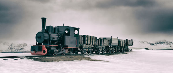 Train on railroad tracks against sky during winter