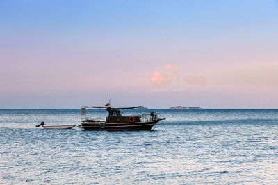 Boat sailing in sea against sky during sunset