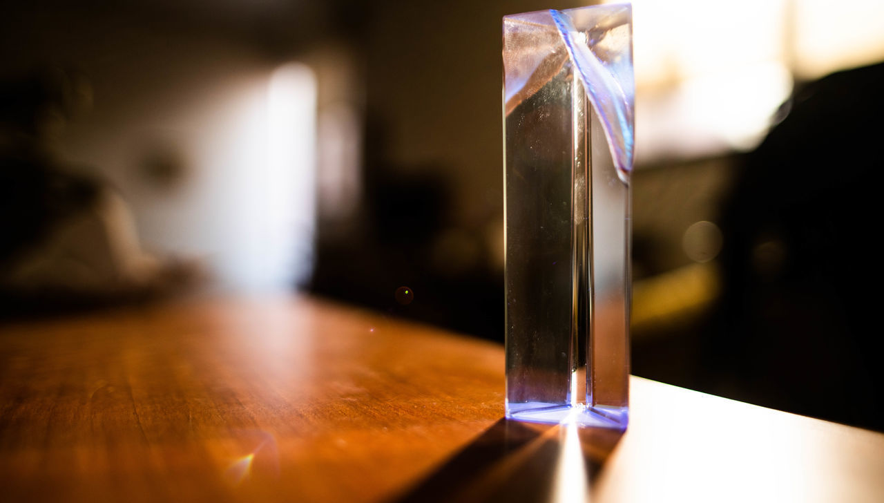 CLOSE-UP OF GLASS TABLE WITH ILLUMINATED LAMP