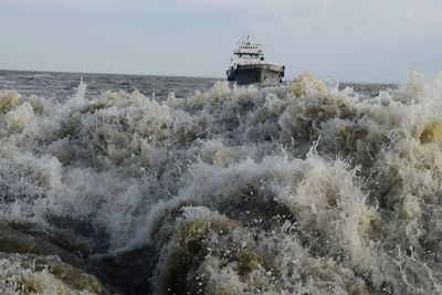 Waves splashing on shore against sky