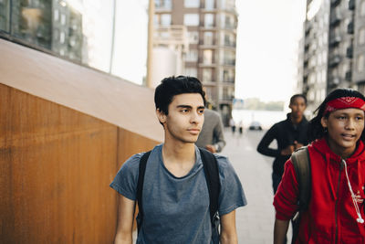 Male friends walking on sidewalk in city