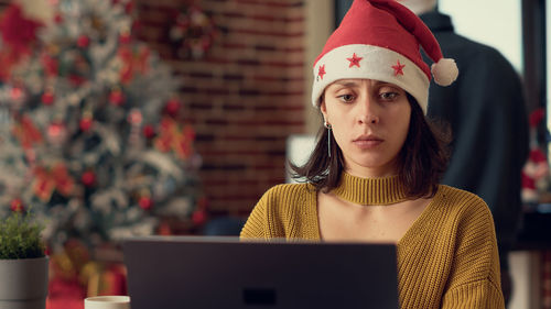 Portrait of young woman using laptop while sitting in cafe