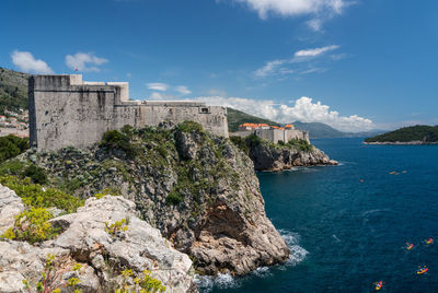 Buildings by sea against sky