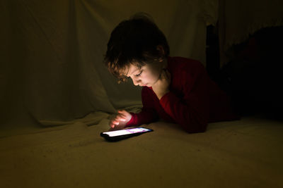 Rear view of boy using mobile phone at home