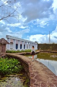 Rear view of woman standing by building against sky