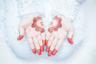 Midsection of bride with henna tattoo on hands