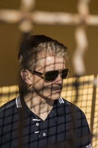 Man wearing sunglasses seen through window