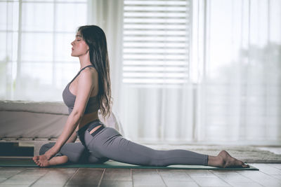 Side view of young woman exercising at home