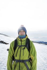 Portrait of man standing on snow covered field against sky