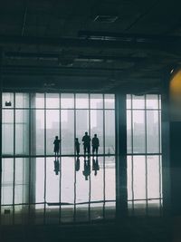 Silhouette people walking in glass building