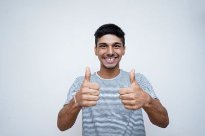 Portrait of smiling young man standing against white background