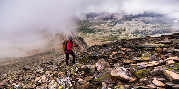 Young woman traveling through the mountains with backpacks on a cloudy day. climbing the mountain on