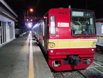 Red train on railroad station platform at night