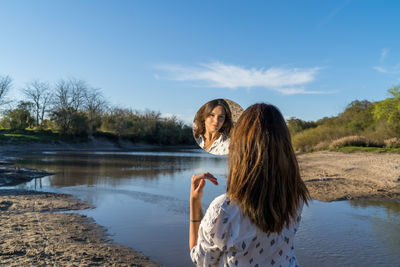 Woman by lake against sky