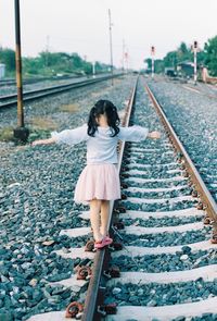 Full length rear view of girl walking on railroad track