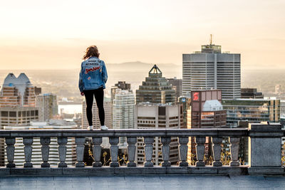 Rear view of woman standing by railing against buildings