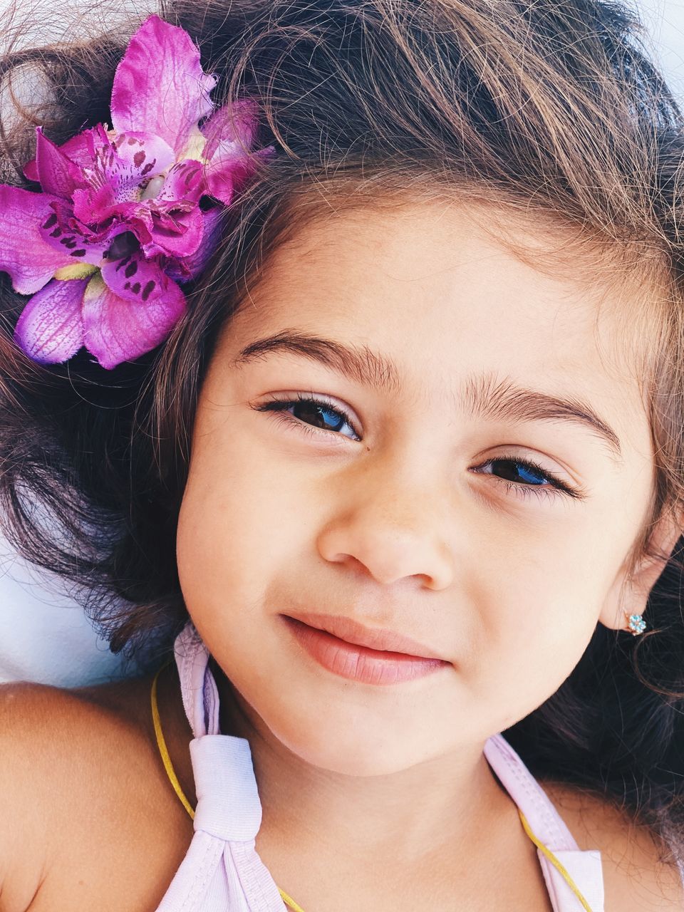 CLOSE-UP PORTRAIT OF A SMILING GIRL WITH PINK FLOWER