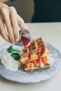 Close-up of hand holding ice cream in plate