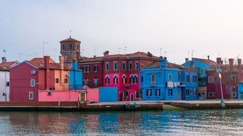 Buildings by river against sky in city