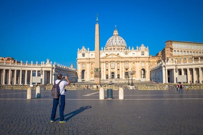 People in front of historical building against blue sky