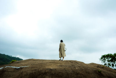 Rear view of woman standing on field against sky