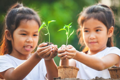 Close-up of girls holding plant in hand outdoors