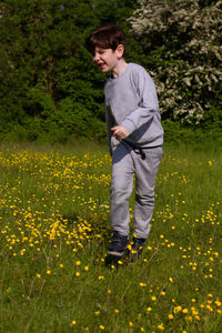 Cute redhead boy  running on a field covered in yellow flowers on a sunny spring day