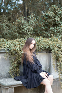 Beautiful young woman sitting by plants