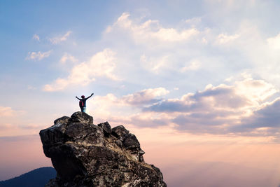 Silhouette man standing on rock against sky at sunset