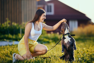 Side view of young woman holding dog