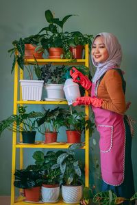 Full length of woman standing on potted plant
