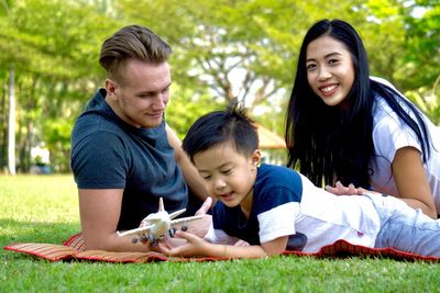 Family lying on grassy field at park