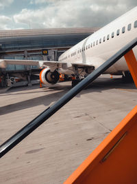 Airplane at airport runway against sky