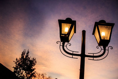 Low angle view of illuminated street light against sky at sunset