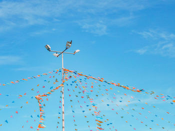 Low angle view of pole and bunting against blue sky