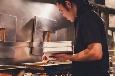 Side view of man preparing food in kitchen