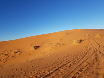 Sand dunes in desert against clear blue sky