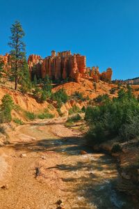 Rock formations on landscape against clear blue sky