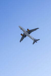 Low angle view of airplane against clear blue sky