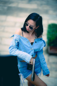 Young woman looking away while standing outdoors