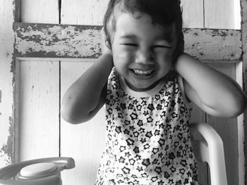 Close-up of cute girl covering ears with hands while sitting against wall