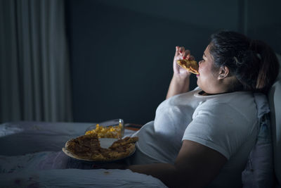 Oversized young woman eating food at home