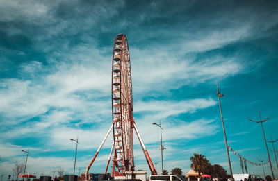 Low angle view of ferris wheel against cloudy sky