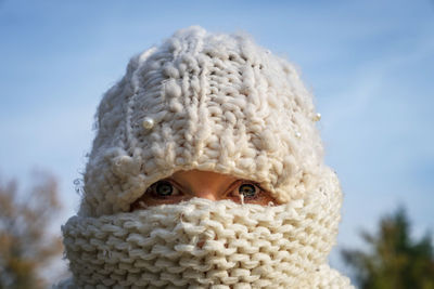 Close-up portrait of woman wearing scarf on face against sky