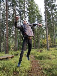 Full length of man with arms raised in forest