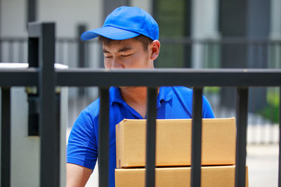 Portrait of man wearing hat against fence